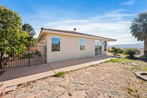 Rear view of house with a patio area, stucco siding, fence, and a gate