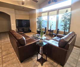 Tiled living room with lofted ceiling and ceiling fan