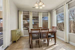 Tiled dining area with plenty of natural light and a notable chandelier