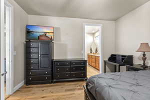 Bedroom with ensuite bath and light hardwood / wood-style flooring