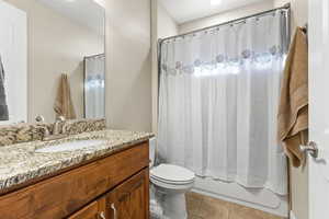 Full bathroom featuring vanity, tile patterned floors, shower / bath combination with curtain, and toilet