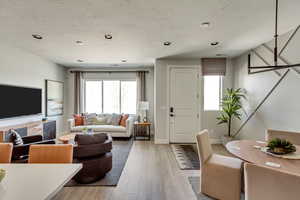 Living room featuring plenty of natural light, a textured ceiling, and light wood-type flooring