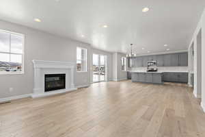 Unfurnished living room with a notable chandelier and light hardwood / wood-style floors