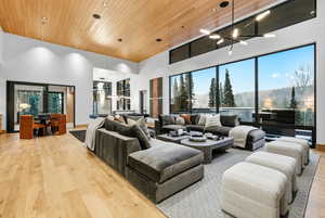 Living room featuring wooden ceiling, light wood finished floors, a high ceiling, and a chandelier
