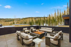 View of patio featuring an outdoor living space with a fire pit and a wooded view