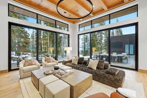 Living area with light wood finished floors, a wood ceiling with exposed beams, a high ceiling, and healthy amount of natural light