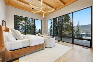 Bedroom with a wooden ceiling with exposed beams, light wood-type flooring, access to outside, and multiple windows