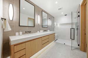 Full bathroom with tile walls, double vanity, a stall shower, light tile patterned floors, and recessed lighting