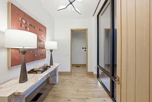 Hall featuring light wood-style floors and a chandelier