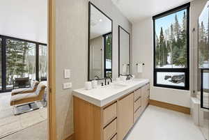Full bathroom featuring plenty of natural light, light tile patterned flooring, double vanity, and tile walls