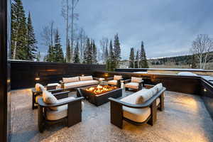 View of patio with an outdoor living space with a fire pit and a view of trees