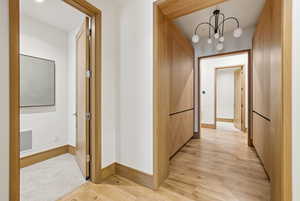 Corridor featuring light wood finished floors and a chandelier