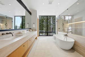 Bathroom with double vanity, a soaking tub, walk in shower, recessed lighting, and expansive windows