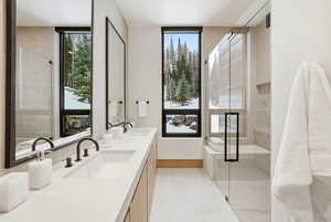 Bathroom featuring double vanity, healthy amount of natural light, and a shower stall