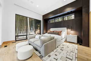 Bedroom with access to exterior, light wood finished floors, wooden walls, and recessed lighting