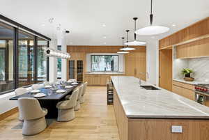 Kitchen featuring light stone countertops, decorative light fixtures, a large island, light wood-style floors, and modern cabinets