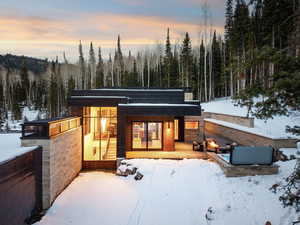 Snow covered house featuring a wooded view