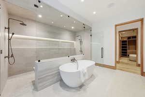 Bathroom with a shower stall, a walk in closet, tile patterned flooring, a freestanding bath, and recessed lighting