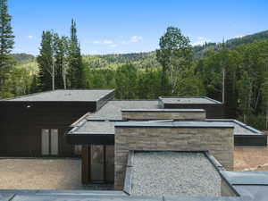 View of front of home featuring a wooded view and stone siding