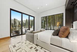 Bedroom featuring access to exterior, light wood-style flooring, and recessed lighting