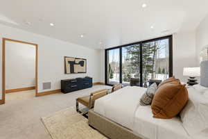 Bedroom featuring expansive windows, light carpet, recessed lighting, and access to exterior