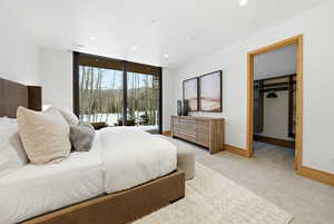 Bedroom featuring a walk in closet, light colored carpet, access to exterior, recessed lighting, and floor to ceiling windows