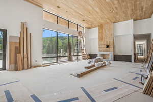 Living area with a towering ceiling, wooden ceiling, and a stone fireplace