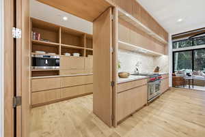 Kitchen with light brown cabinetry, stainless steel appliances, modern cabinets, recessed lighting, and light wood-style flooring