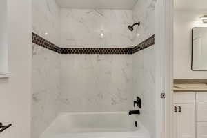 Bathroom featuring tiled shower / bath and vanity