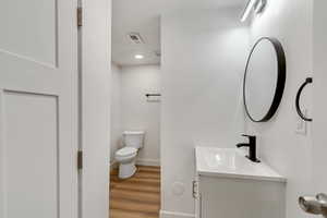 Bathroom with hardwood / wood-style flooring, vanity, and toilet