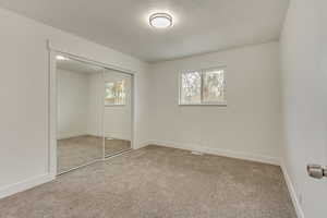 Unfurnished bedroom with multiple windows, carpet floors, and a closet