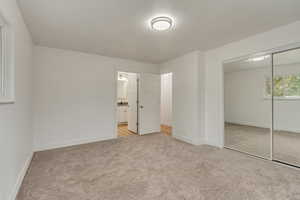 Unfurnished bedroom with light carpet, ensuite bath, and a closet