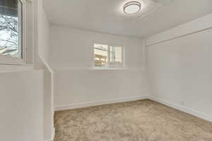 Unfurnished room featuring light carpet and a textured ceiling