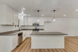 Kitchen featuring white cabinetry, appliances with stainless steel finishes, a center island, and pendant lighting