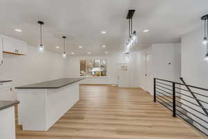 Kitchen featuring white cabinetry, hanging light fixtures, and light hardwood / wood-style floors