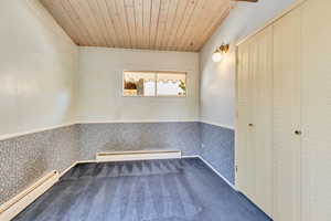 Unfurnished room with wood ceiling, a baseboard radiator, and carpet flooring