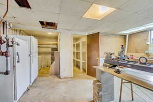 Kitchen with white refrigerator, a drop ceiling, and washer / clothes dryer