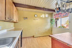 Kitchen with baseboard heating, beam ceiling, hanging light fixtures, and wooden ceiling