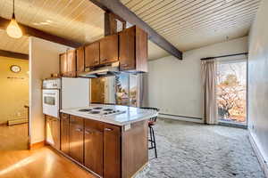 Kitchen featuring beam ceiling, hanging light fixtures, white appliances, and a baseboard heating unit