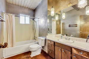 Full bathroom featuring toilet, wood ceiling, tile walls, vanity, and shower / bath combo with shower curtain