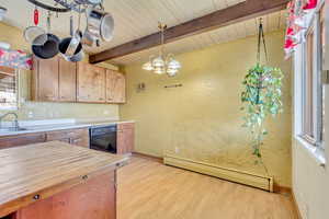 Kitchen with sink, black dishwasher, decorative light fixtures, a baseboard radiator, and light wood-type flooring