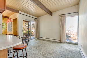 Dining space with beamed ceiling, carpet floors, and baseboard heating