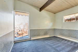 Spare room with lofted ceiling with beams, a baseboard radiator, carpet floors, and wooden ceiling