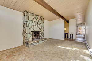 Unfurnished living room featuring a stone fireplace, wooden ceiling, a baseboard radiator, carpet flooring, and beamed ceiling