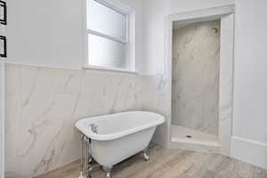 Bathroom featuring separate shower and tub, tile walls, and hardwood / wood-style flooring