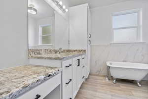 Bathroom featuring hardwood / wood-style flooring, a tub, vanity, and tile walls