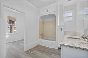 Bathroom with hardwood / wood-style flooring, tiled shower / bath combo, and vanity