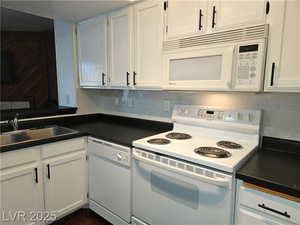 Kitchen with white cabinetry, sink, white appliances, and decorative backsplash