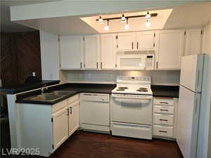 Kitchen featuring white cabinetry, dark hardwood / wood-style flooring, sink, and white appliances