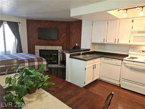 Kitchen featuring sink, white cabinets, white appliances, and kitchen peninsula